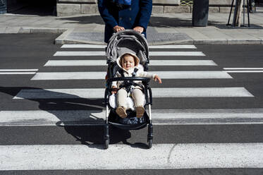 Vater mit Baby im Kinderwagen beim Überqueren der Straße in der Stadt - PGF00154