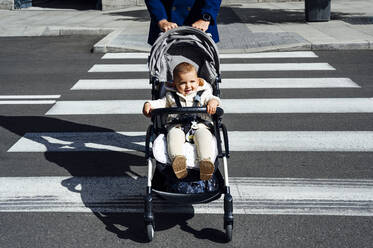 Vater mit lächelndem Baby im Kinderwagen beim Überqueren der Straße in der Stadt - PGF00155