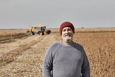 Smiling farmer standing at field during sunny day - ZEDF03965