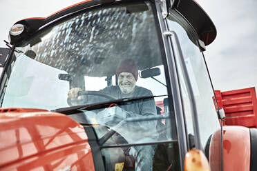 Lächelnder Bauer bei der Ernte mit Traktor auf dem Bauernhof - ZEDF03972