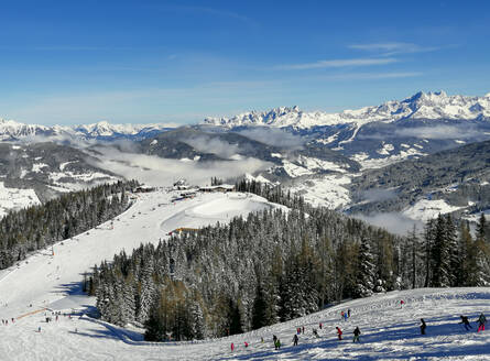 Österreich, Salzburg, St. Johann im Pongau, Skifahrer fahren in den schneebedeckten Bergen den Hang hinunter - WWF05458