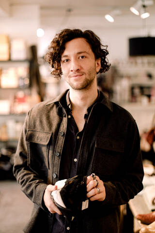 Portrait of male customer buying shoe at retail store stock photo