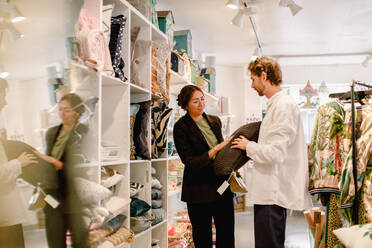 Man and woman looking at cushion in retail store - MASF19972