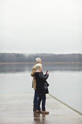 Älteres Paar in voller Länge am See stehend gegen den klaren Himmel - MASF19985