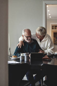 Lächelndes älteres Paar im Gespräch am Esstisch im Wohnzimmer - MASF20002