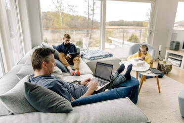 Hochformatige Ansicht eines Vaters und seiner Kinder bei der Nutzung der drahtlosen Technologie zu Hause - MASF20028