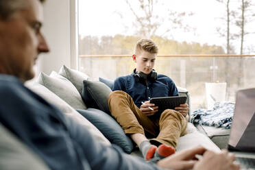 Jugendlicher mit digitalem Tablet auf dem Sofa zu Hause - MASF20029