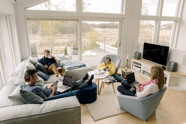 High angle view of family using technology while sitting in living room - MASF20032