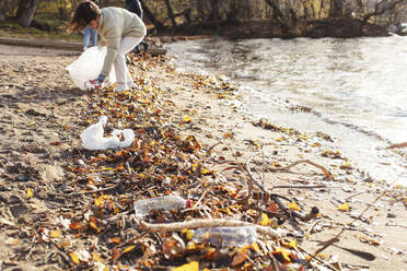 Freiwillige Helferin sammelt Plastikmüll am See - MASF20037