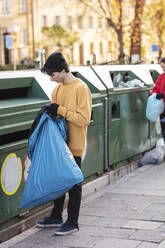 Junge männliche und weibliche Freiwillige, die Plastikmüll in den Mülleimer werfen - MASF20039