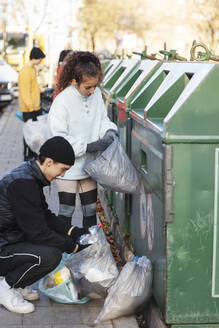 Junge Umweltschützerinnen und -schützer werfen Recycling-Müll in die Mülltonne - MASF20040