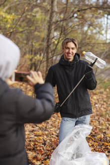 Teenager fotografiert Freund mit Plastikflasche im Park im Herbst - MASF20050