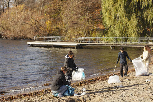 Männliche und weibliche Freunde sammeln Plastikmüll am See - MASF20054
