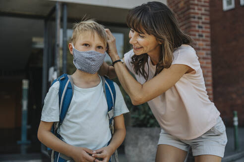 Mother helping son to wear protective face mask while going to school - MFF06359