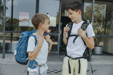 Brüder schauen sich an, während sie vor dem Schulgebäude stehen - MFF06366