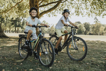 Brüder beim Radfahren im öffentlichen Park an einem sonnigen Tag - MFF06373