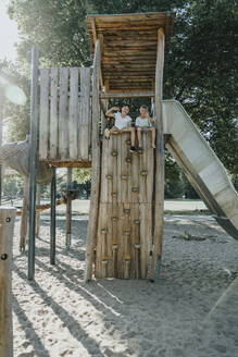 Brothers sitting on wooden built structure in public park - MFF06393