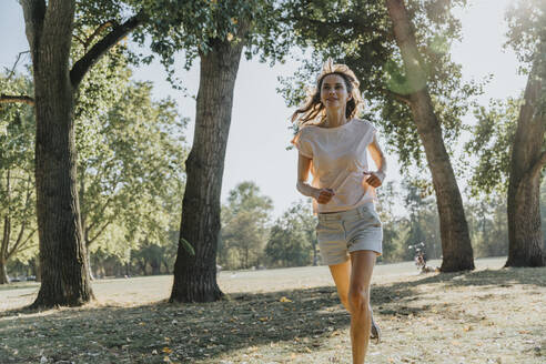 Mature woman jogging in public park on sunny day - MFF06411