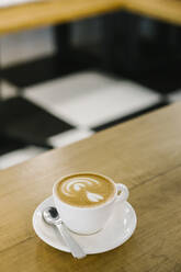 Cappuccinotasse mit Löffel auf dem Tisch in einem Kaffeehaus - XLGF00610