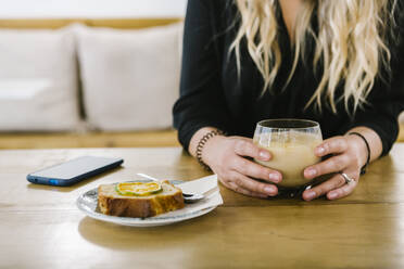 Mittlere erwachsene Frau bei Kaffee und Kuchen in einem Café sitzend - XLGF00611