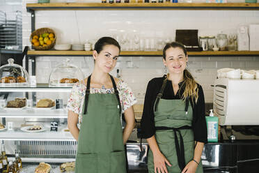 Smiling women standing by counter at coffee shop - XLGF00618