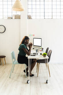 Geschäftsfrau, die im Büro sitzend am Laptop arbeitet - GIOF09232