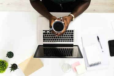 Geschäftsfrau trinkt Kaffee bei der Arbeit im Büro - GIOF09237