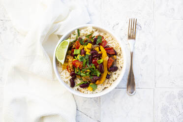 Bowl of Mexican rice with tomatoes, bell pepper, tofu, kidney beans, corn, scallion and lime - LVF09033