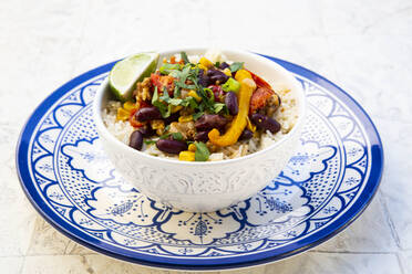 Bowl of Mexican rice with tomatoes, bell pepper, tofu, kidney beans, corn, scallion and lime - LVF09035