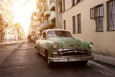 Kuba, Provinz La Habana, Havanna, Pastellgrüner Oldtimer, geparkt auf der Straße bei Sonnenuntergang - RNF01297