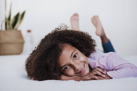 Little girl lying on front in bedroom at home stock photo