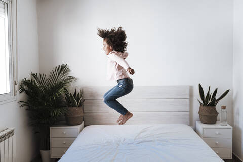 Cute girl jumping on bed in bedroom at home stock photo