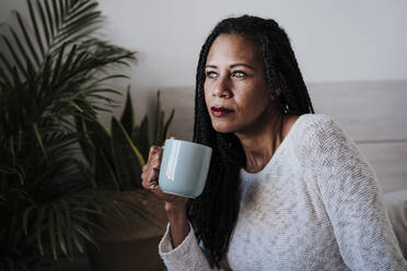 Mature woman drinking coffee while sitting at home - EBBF00955