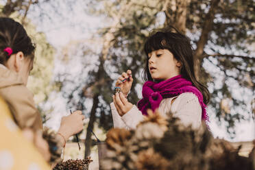 Niedliche Mädchen färben Tannenzapfen mit Pinseln im Park - ERRF04611