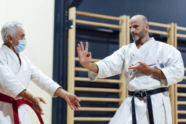 Männlicher Schüler übt Karate mit seinem Ausbilder im Unterricht - OCMF01789