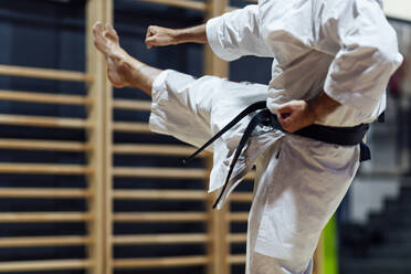 Mature man kicking while practicing karate in class - OCMF01790