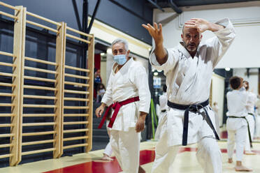 Ausbilder von männlichem Schüler, der Karate im Unterricht übt - OCMF01792