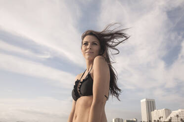 Portrait of attractive young woman in black bikini walking on