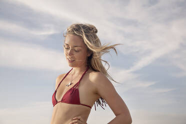 Young woman with eyes closed standing against clear sky - AJOF00325