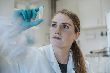 Young woman examining test tube while standing at laboratory - MFF06449