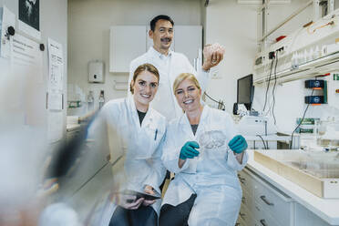 Team of scientist holding glass sample and anatomy of human brain at laboratory - MFF06486