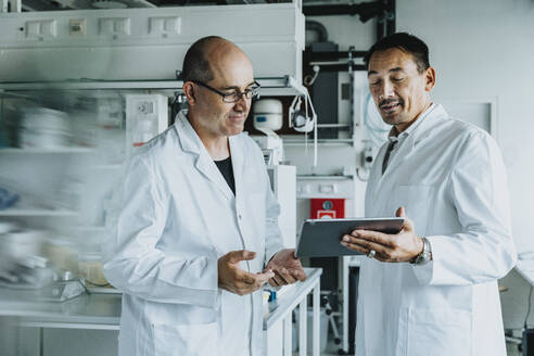 Scientist using digital tablet while standing at laboratory  - MFF06534