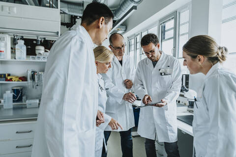 Wissenschaftler bei der Arbeit mit einem digitalen Tablet, während er im Labor steht, lizenzfreies Stockfoto
