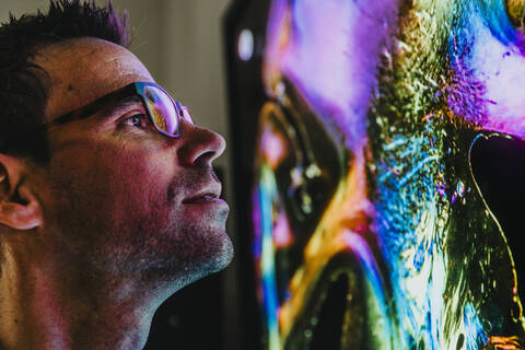 Scientist wearing eyeglasses examining projection of human brain with nerve fiber while standing at laboratory stock photo