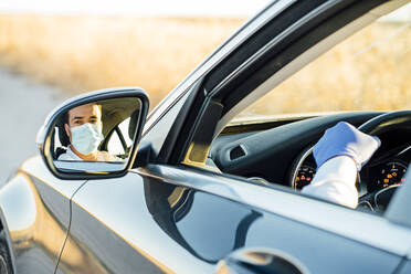 Reflection of man wearing protective mask on side-view mirror - CJMF00338