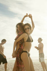 Freunde tanzen am Strand an einem sonnigen Tag - AJOF00352