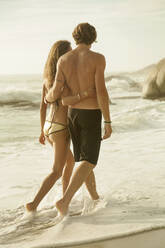 Paar umarmt sich beim Spaziergang im Wasser am Strand - AJOF00359