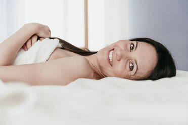 Lächelnde Frau auf dem Bett liegend zu Hause - EBBF00995