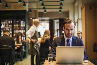 Businessman using laptop while sitting in restaurant - MASF20057