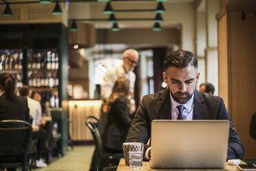 Businessman using laptop in restaurant - MASF20059